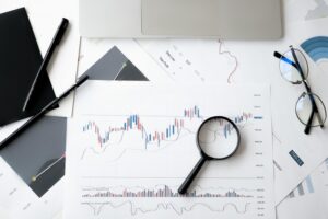 Financial charts with magnifying glass, notebook, and laptop showing real estate investment analysis